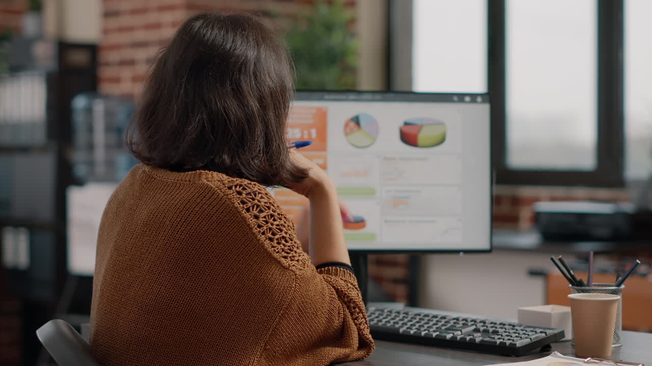 Woman working with business analytics charts on computer in office