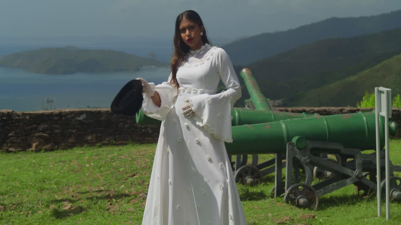 A young lady dressed in a vintage-style wedding dress explores the ruins of a fort.