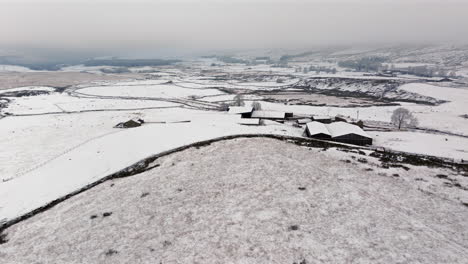 establishing drone shot of yorkshire dales farm on snowy morning uk