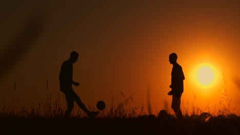 Dos-Niños-Jugando-Al-Fútbol-Al-Atardecer.-Silueta-De-Niños-Jugando-Con-Una-Pelota-Al-Atardecer.-El-Concepto-De-Una-Familia-Feliz.