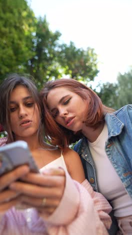 young women looking at smartphone outdoors