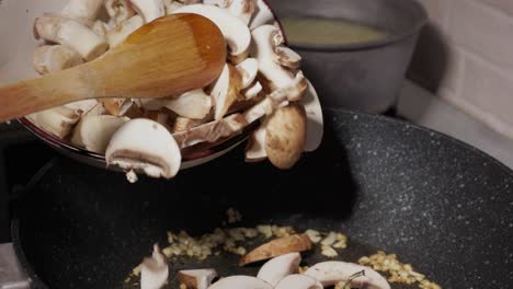 pouring sliced and chopped mushrooms into frying pan - close up