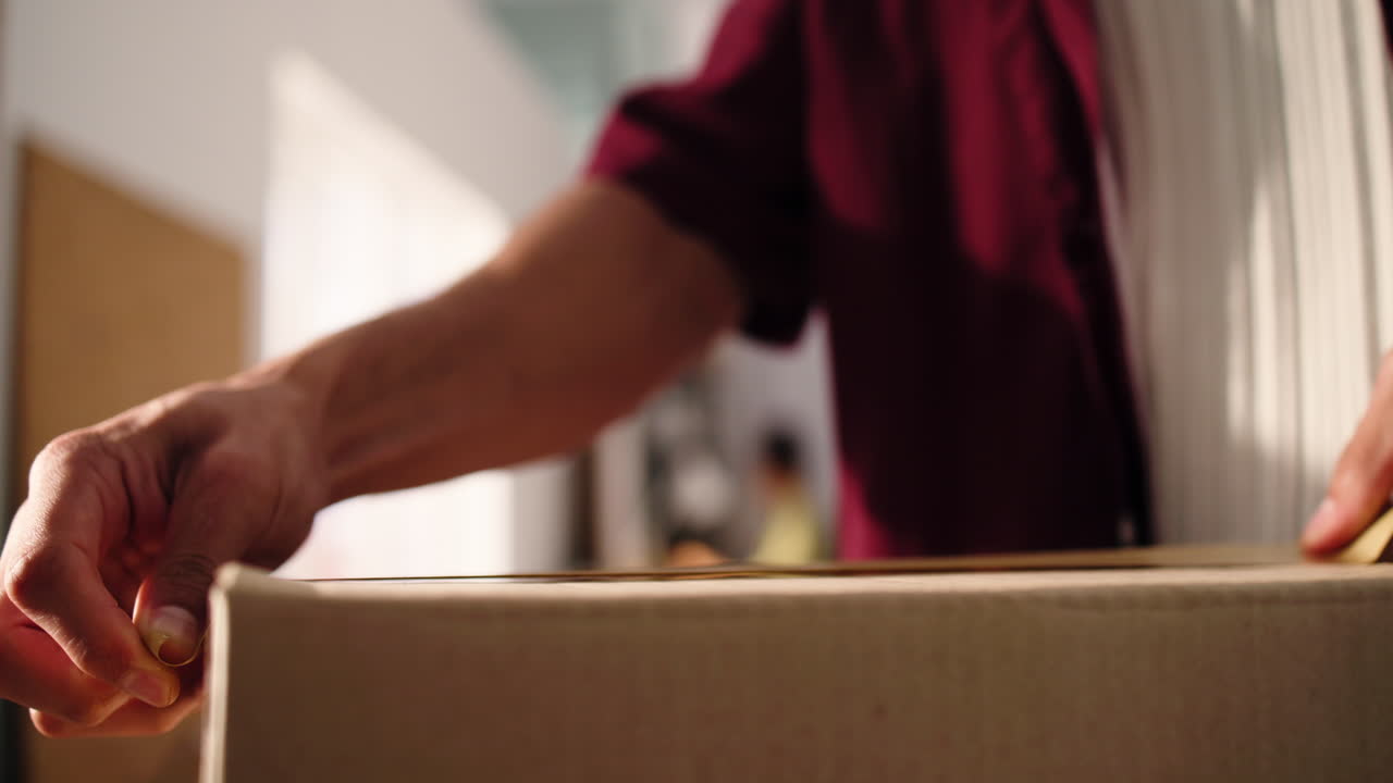 Close Up of Hands Taping a Cardboard Box