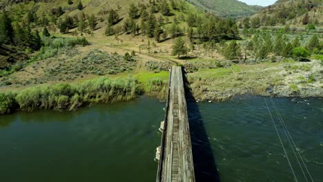 us, oregon, spray, service creek, 2025-05-07 - drone view of a private gated wooden bridge crossing service creek in north central oregon. it leads deep into the mountains to a ranch