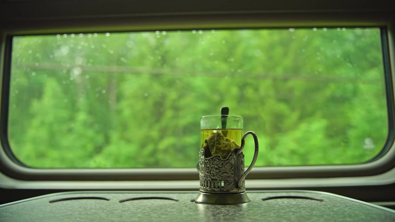 Tè caldo in un portabicchieri tradizionale su un treno in movimento con vista su una foresta verde