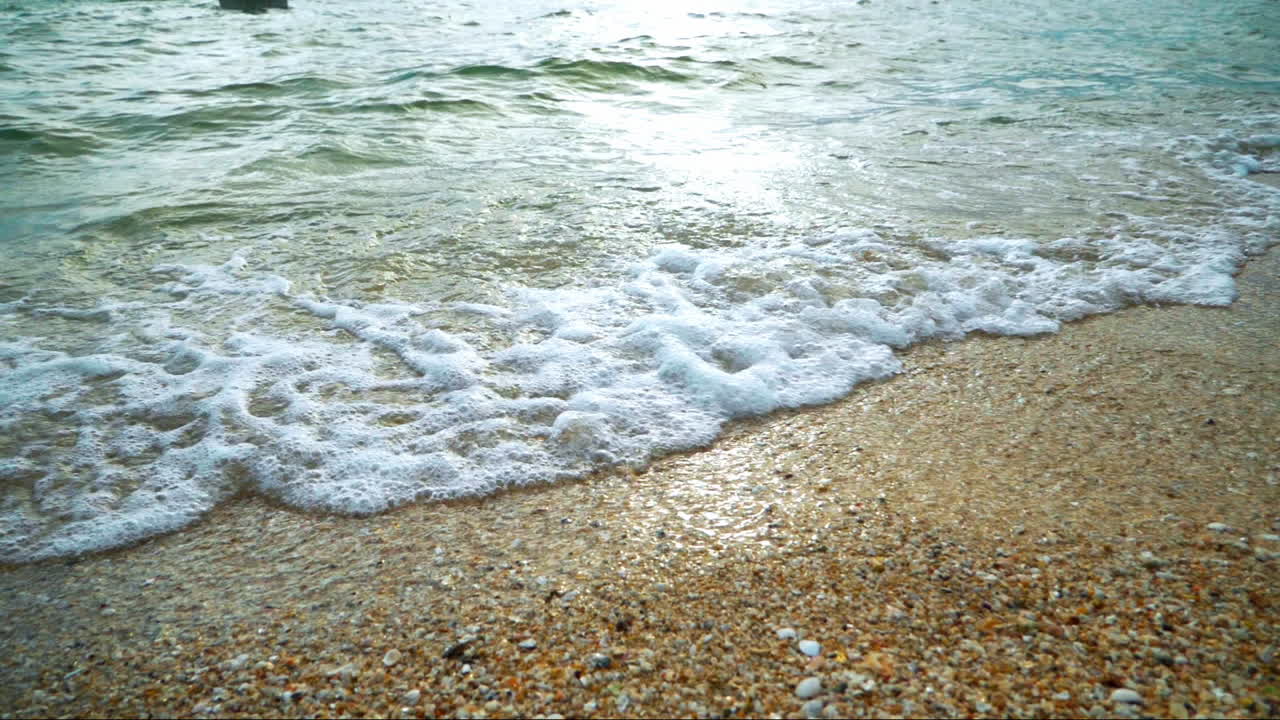 해가 지는 동안 열대 지방의  ⁇  모래 해변의 해안에 도달하는 파도와 함께 아름다운 해변