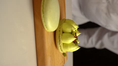 el chef de pastelería francés agrega pistachos a los macarrones, video en cámara lenta, video vertical