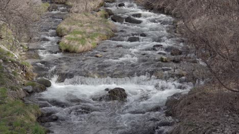 un arroyo fluye sobre piedras y pequeños obstáculos en un lecho de arroyo natural