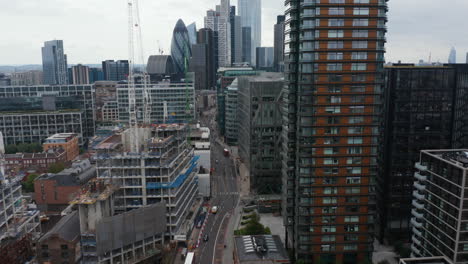 Forwards-descending-fly-through-business-district.-Tower-cranes-on-construction-site-of-new-building.-Tall-skyscrapers-in-City-financial-district-in-background.-London,-UK