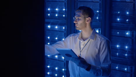 técnico en la sala de servidores digitales del centro de datos controlando el trabajo de los gabinetes de servidores de rack con una tableta. ingeniero profesional de servidores en el trabajo.