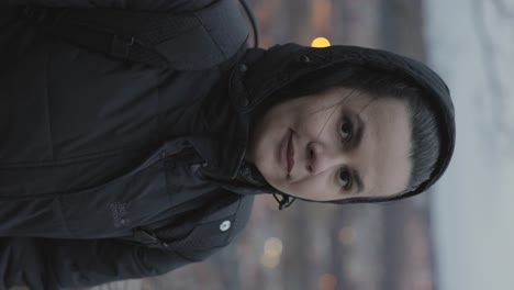 - mujer europea vertical con chaqueta de invierno con capucha admirando el paisaje urbano de jonkoping en suecia