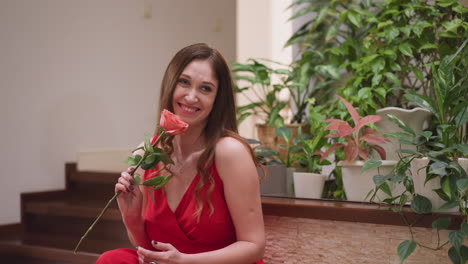 una dama posa colocando una rosa de cara para el arte. el modelo en vestido rojo inspira al pintor a encapsular el encanto seductor a través de trazos meticulosos de pincel