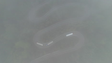 aerial view of trucks driving on winding mountain road in romania, with clouds and fog