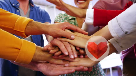 icono de corazón rojo sobre la sección media de diversos colegas de oficina poniendo sus manos juntas en la oficina