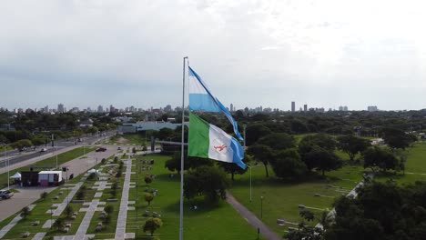 aerial orbit of argentina flag reveals park, modern city, and roadway