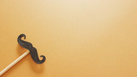 Video-of-false-moustache-on-stick-on-yellow-background-with-copy-space