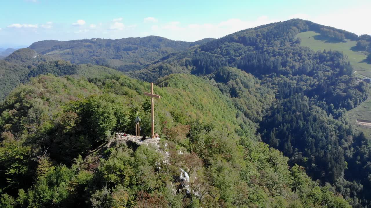 숲으로 둘러싸인 산 꼭대기에 있는 기독교 십자가