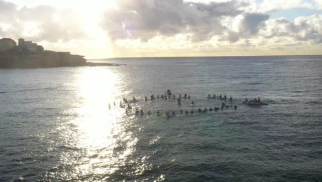 Eine-Gruppe-Von-Menschen-Hält-Während-Des-Sonnenaufgangs-In-Bondi,-Australien,-Eine-Paddel-Gedenkzeremonie-Auf-Dem-Wasser-Ab