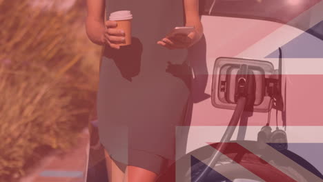 flag of great britain over woman using smartphone and charging electric car