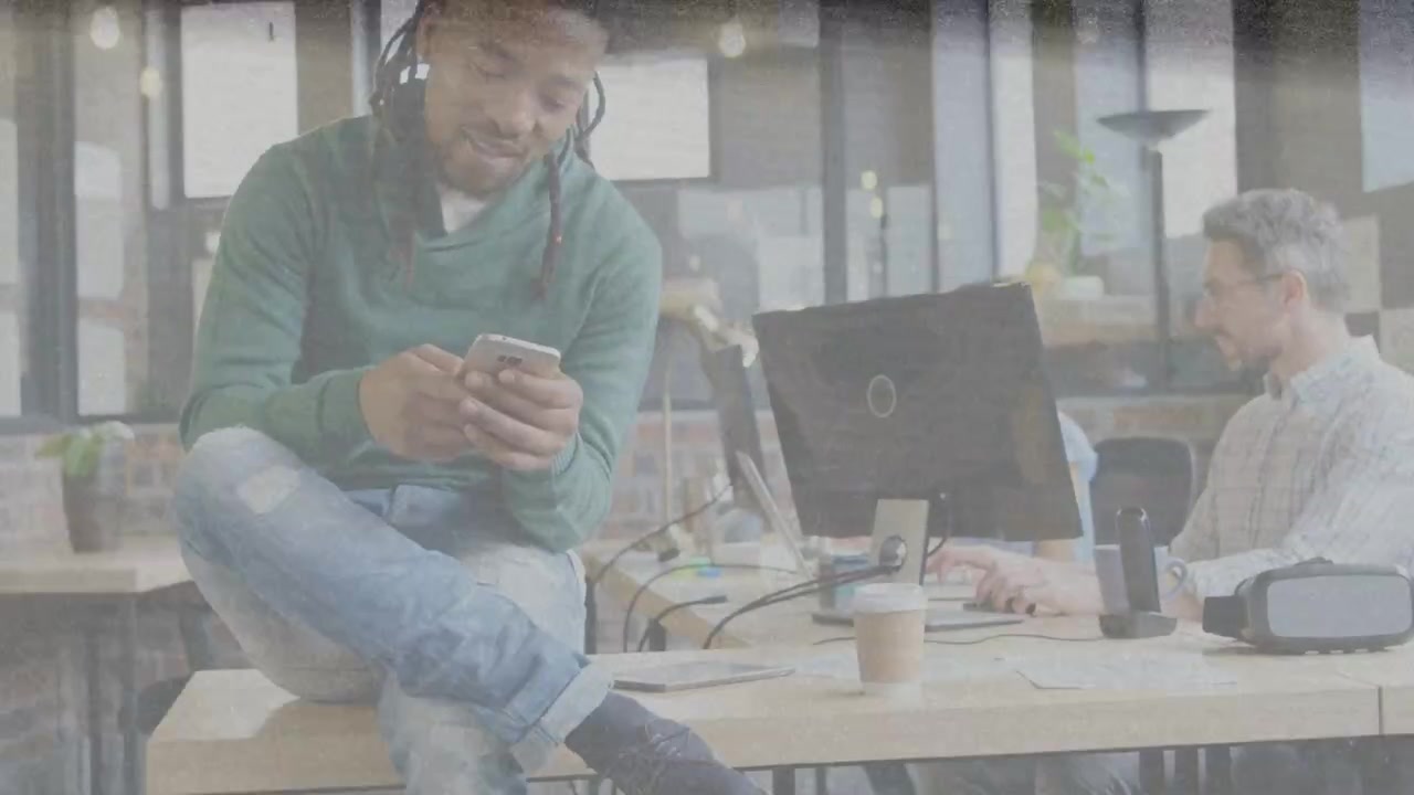Man sitting on desk tapping phone reviewing app, initiating animated UI and charts in tech office