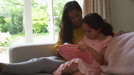 Madre-E-Hija-En-Casa-Sentadas-En-El-Sofá-Jugando-Juntas-A-Un-Juego-De-Computadora-Portátil