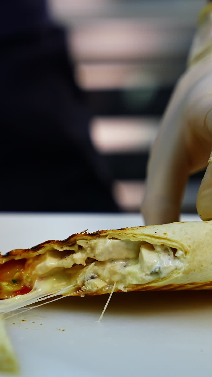 Tasty shawarma with tomatoes, peppers and sauces that make up its composition are laid out on a lacquered table cut in a half. Vertical video