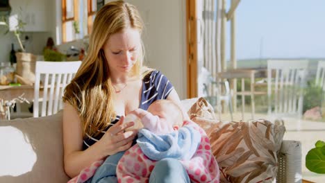 front view of mid adult caucasian mother feeding milk her baby from bottle in a comfortable home 4k