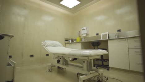 empty medical examination room with stretcher and cabinets under white lamp