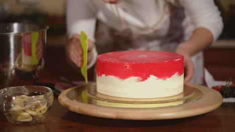 woman decorating a red and white layer cake