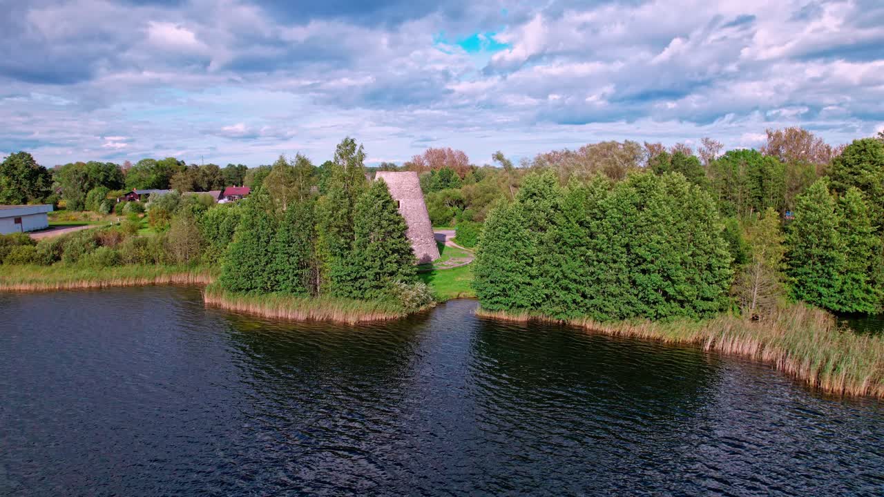 Exploring a historic tower near the serene waters in Latvia's countryside