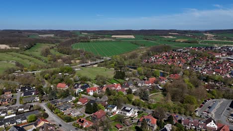 aerial view of american housing area with agricultural farm fields in background. sunny day and blue sky in spring season. rising drone wide shot. countryside in rural area of usa.
