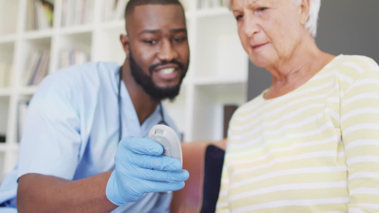 Video of midsection of african american male doctor checking glucose level to caucasian senior woman