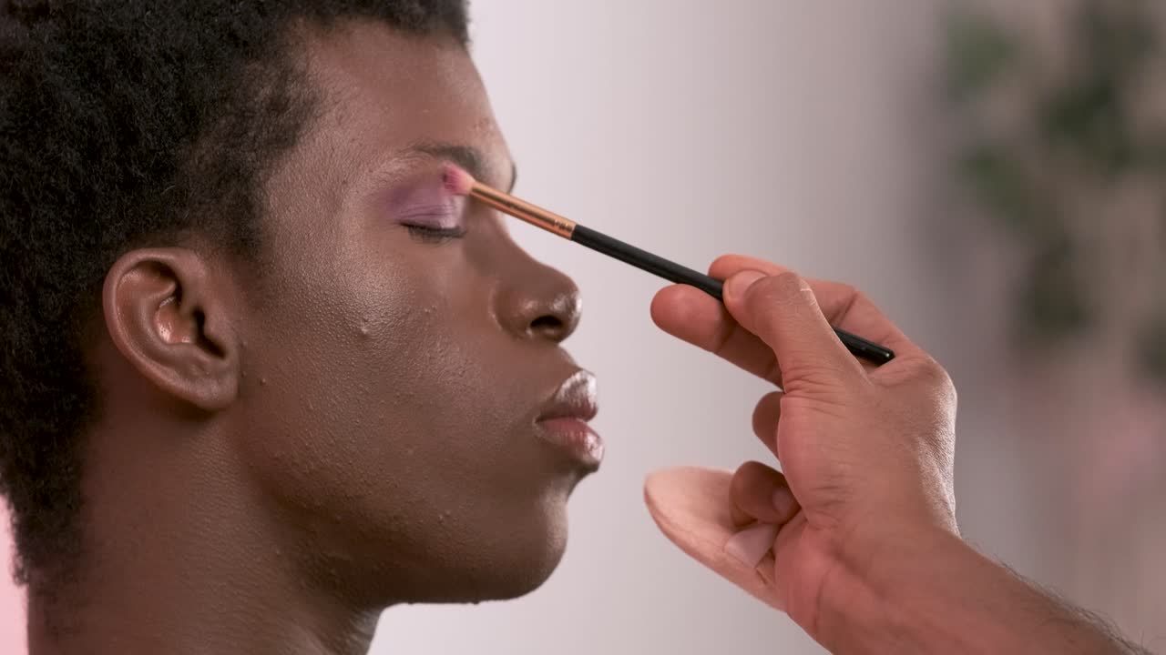 Crop visagiste filling in eyebrows of black transgender