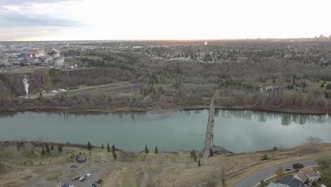 Rundel-Park-Panaramic-left-fly-over-Oil-Refinery-in-the-top-left-horizon-next-to-biohazard-pools-next-to-golf-course-across-a-river-bridge-park-with-low-rise-residential-buildings---community-center