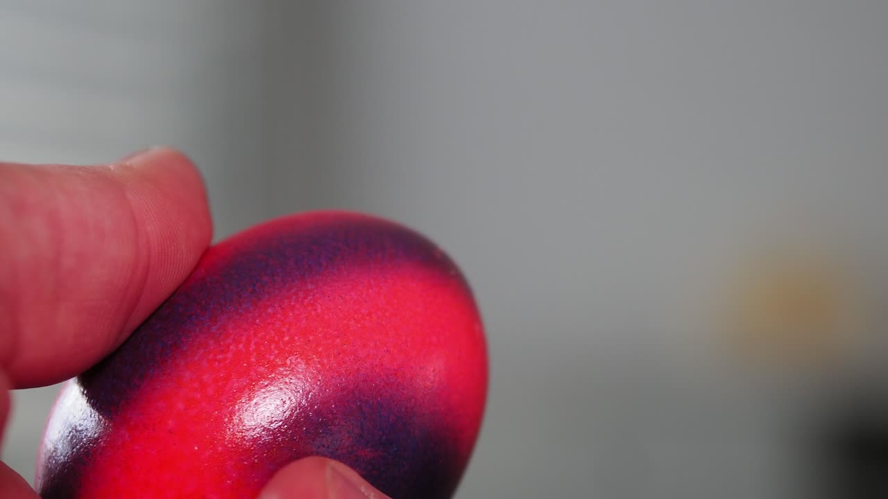 persona golpeando dos huevos de pascua pintados de colores el uno contra el otro, cerca de la cámara lenta