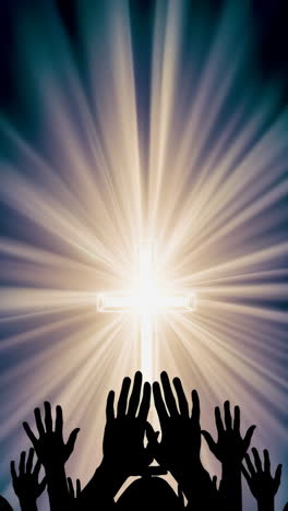 hands raised in prayer towards a glowing cross
