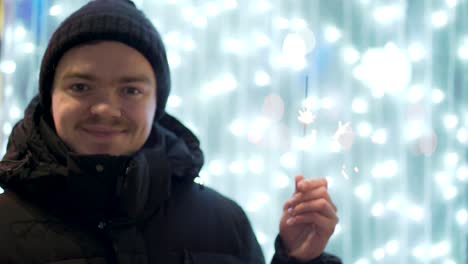 hombre con chispa delante de las luces de navidad