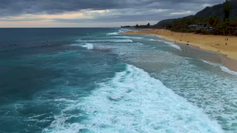 Volando-Bajo-Sobre-Las-Olas-Rompiendo-En-La-Orilla-De-La-Playa-En-El-Parque-De-La-Playa-Ehukai,-Famoso-Destino-De-Surf,-Ohau