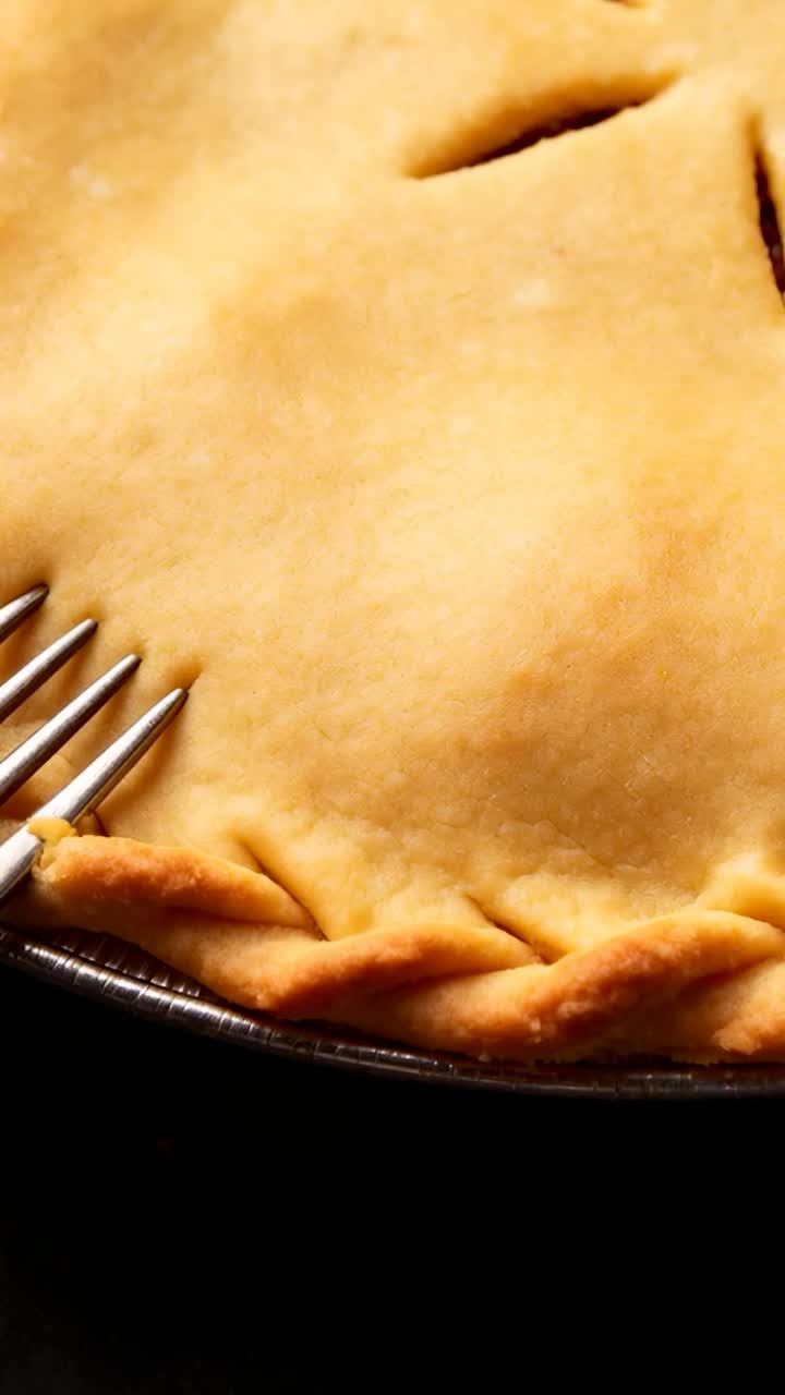 Video verticale: Entrando da sinistra, una forchetta preme la pasta per crostata con dei fori su un bancone, formando un bordo ondulato