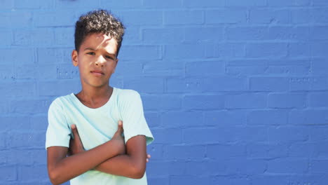 a young african american boy stands against blue background, copy space