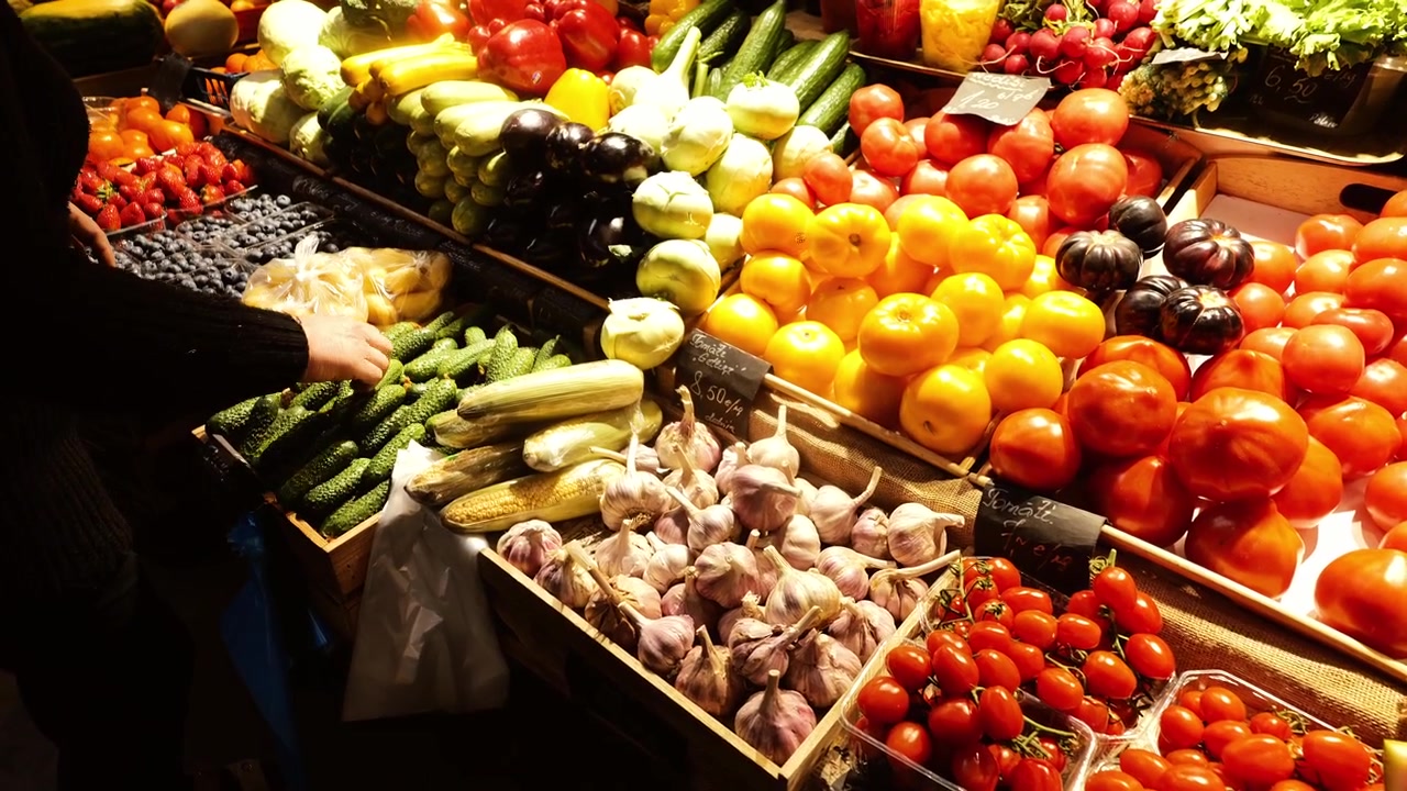 Un acheteur sélectionne des produits parmi des légumes colorés sur un marché traditionnel de Riga