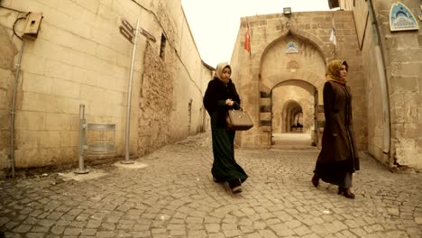 two muslim girls go in narrow ancient stone streets of urfa