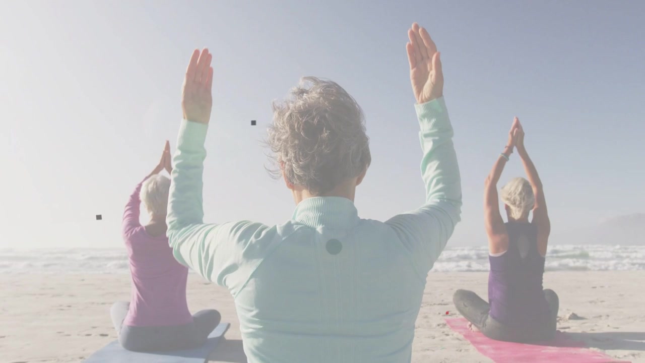 Ortadaki kadın kollarını kaldırıyor ve yanındaki kadınlara liderlik ediyor, onlar da dalgalara karşı matlar üzerinde yoga yapıyor.