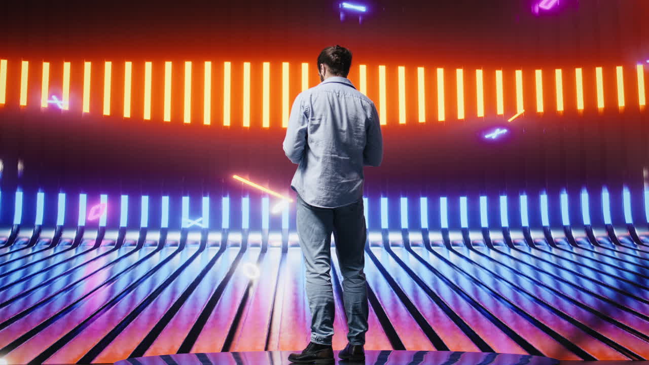 Casual young guy looking around at the glowing neon lights with vibrant colors