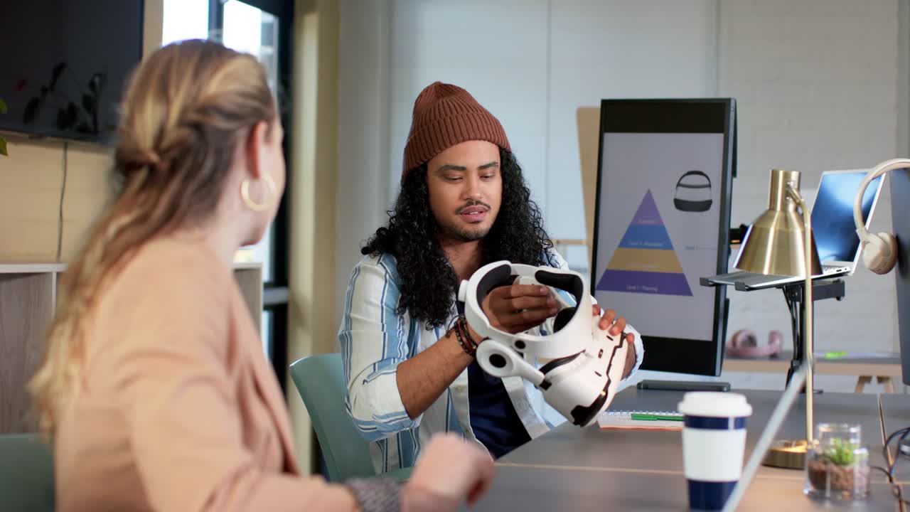 Female colleague reaching and handing VR headset to male peer during meeting, driving design review