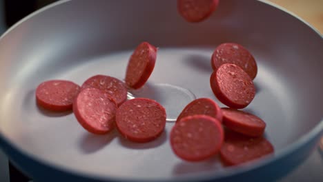 sliced turkish sausages (sucuk) fall into the pan in slow motion.