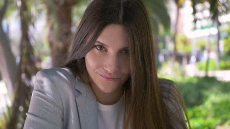 Retrato de una hermosa mujer joven sonriendo y mirando a la cámara al aire libre