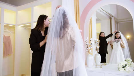 asian and caucasian woman in wedding dress shop