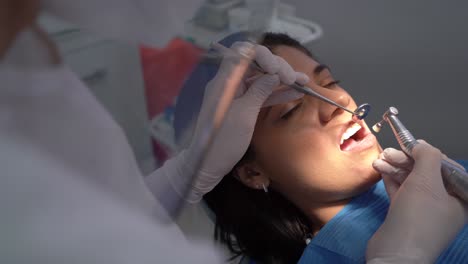 Crop-dentist-curing-tooth-of-female-patient