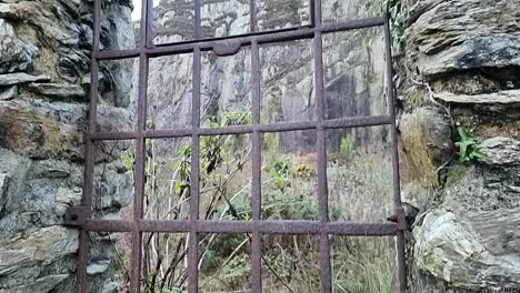 Ornate-wrought-iron-arched-window-frame-masonry-remains-in-Welsh-quarry-brickwork-factory-ruins